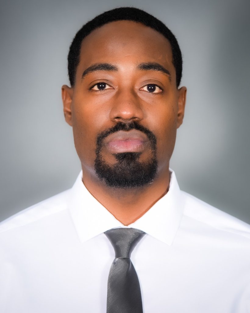 Portrait of Jibreel Rice, founder of Rice Logic Consulting, in a white shirt and dark gray tie.